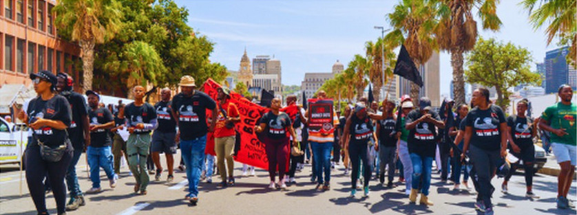 Community members marching through Cape Town streets with banners and placards